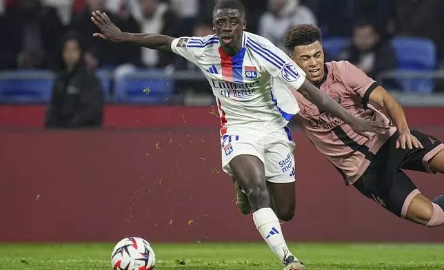Lyon's Sael Kumbedi, left, duels for the ball with PSG's Desire Doue during the French League One soccer match between Lyon and Paris Saint-Germain at the Groupama stadium, outside Lyon, France, Sunday, Feb. 23, 2025. (AP Photo/Laurent Cipriani)