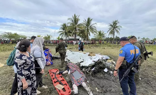 The body of a victim is covered with a blanket as members of security forces inspect the site where wreckage of airplane is seen in a rice field in Maguindanao del Sur province, Philippines, after officials say a U.S. military-contracted plane has crashed in a rice field in the southern Philippines, killing all four people on board, on Thursday Feb. 6, 2025. (Sam Mala/UGC via AP)