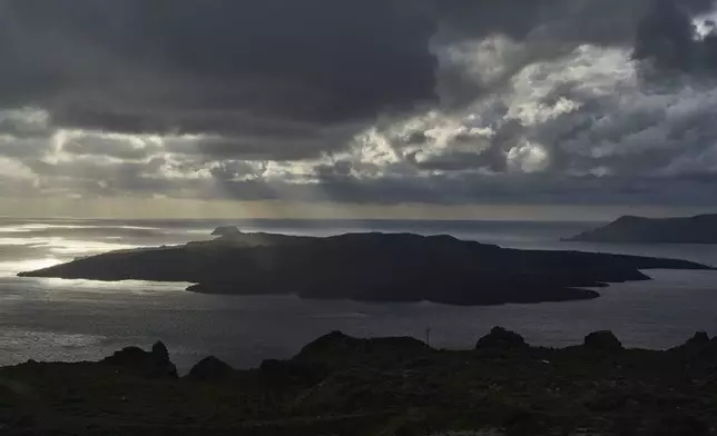 Sun rays illuminate the volcanic islet of Nea Kameni, part of the earthquake-struck island of Santorini, Greece, Tuesday, Feb. 4, 2025. (AP Photo/Petros Giannakouris)