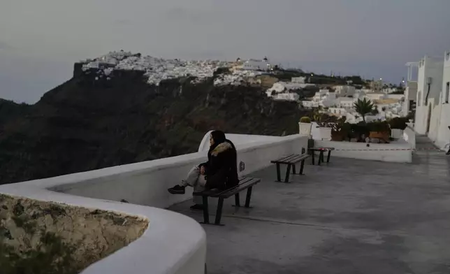 A tourist sits at Firostefani as Greek authorities are taking emergency measures in response to intense seismic activity on the popular Aegean Sea holiday island of Santorini, southern Greece, Monday, Feb. 3, 2025. (AP Photo/Petros Giannakouris)