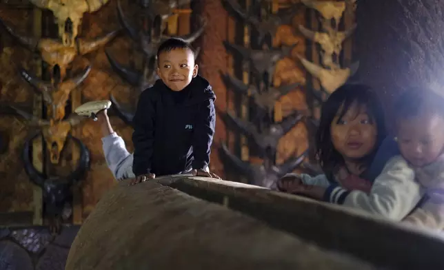 Children play by a traditional log drum in the house of the Angh, or chief, at Longwa village on the India-Myanmar border in the northeastern India state of Nagaland, Thursday, Dec.12, 2024. (AP Photo/Yirmiyan Arthur)