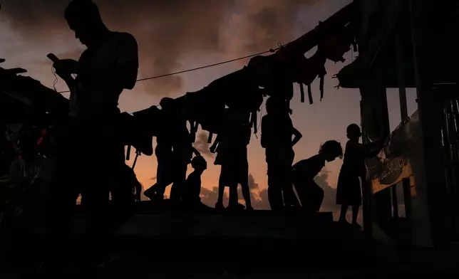 Migrants wind down during sunset on Gardi Sugdub Island, on Panama's Caribbean coast, Sunday, Feb. 23, 2025, where they will overnight before attempting to board boats to Colombia the following day after turning back from southern Mexico, abandoning hopes of reaching the U.S. amid President Trump's crackdown on migration. (AP Photo/Matias Delacroix)