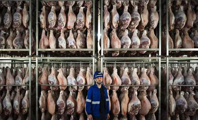 Víctor Razuri, 41, from Peru, poses in a ham drying plant in Guissona, Lleida, Spain, Thursday, Feb. 20, 2025. Inside a cavernous production plant in northeastern Spain, among millions of legs of Spanish ham traveling down hooks and conveyer belts, people from 62 nationalities work side by side to keep a successful food company humming. (AP Photo/Joan Mateu Parra)