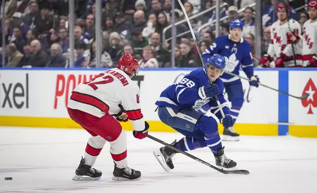 Toronto Maple Leafs right wing William Nylander (88) passes the puck away from Carolina Hurricanes centre Jesperi Kotkaniemi (82) during second period NHL hockey action in Toronto, Saturday, Feb. 22, 2025.(Arlyn McAdorey/The Canadian Press via AP)