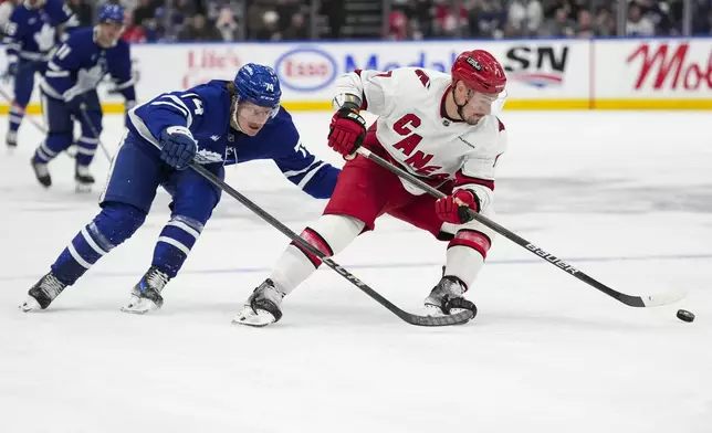 Toronto Maple Leafs centre Bobby McMann (74) and Carolina Hurricanes defenseman Dmitry Orlov (7) chase after the puck during second period NHL hockey action in Toronto, Saturday, Feb. 22, 2025. (Arlyn McAdorey/The Canadian Press via AP)