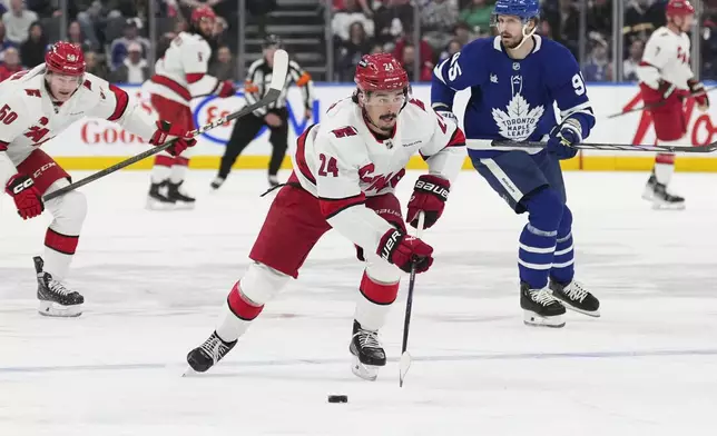 Carolina Hurricanes center Seth Jarvis (24) skates with the puck as Toronto Maple Leafs defenseman Oliver Ekman-Larsson (95) pursues during first-period NHL hockey game action in Toronto, Saturday, Feb. 22, 2025. (Arlyn McAdorey/The Canadian Press via AP)