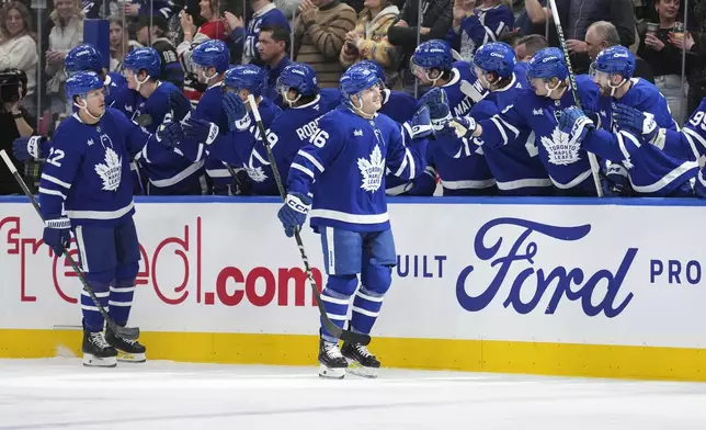 Toronto Maple Leafs' Alex Steeves (46) Jake McCabe (22) are congratulated by teammates after Steeves' goal against the Carolina Hurricanes during first-period NHL hockey game action in Toronto, Saturday, Feb. 22, 2025. (Arlyn McAdorey/The Canadian Press via AP)