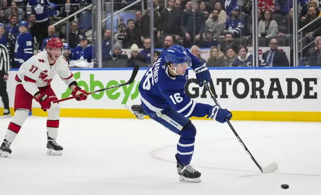 Toronto Maple Leafs right wing Mitch Marner (16) shoots while Carolina Hurricanes right wing Andrei Svechnikov (37) looks on during second-period NHL hockey game action in Toronto, Saturday, Feb. 22, 2025. (Arlyn McAdorey/The Canadian Press via AP)