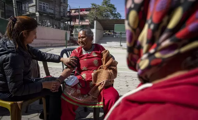 Kanchi Thapa Magar, 70, center, gets her blood pressure level checked during a break at the Ujyalo Community learning center in Kathmandu, Nepal, Feb. 6, 2025. (AP Photo/Niranjan Shrestha)
