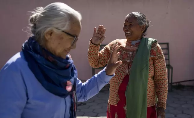 Kanchi Thapa Magar, 70, right, waves as she leaves Ujyalo Community learning center in Kathmandu, Nepal, Feb. 6, 2025. (AP Photo/Niranjan Shrestha)