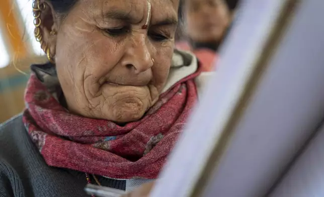 Kamala K.C, 66, writes on a note book during a class at the Ujyalo Community learning center in Kathmandu, Nepal, Feb. 3, 2025. (AP Photo/Niranjan Shrestha)