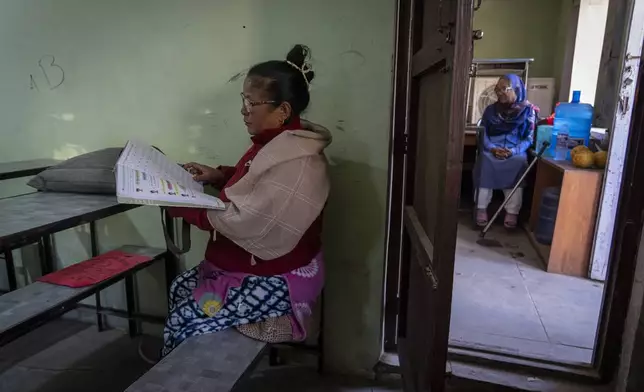 An elderly woman reads a text book before the start of her class at the Ujyalo Community learning center in Kathmandu, Nepal, Feb. 6, 2025. (AP Photo/Niranjan Shrestha)