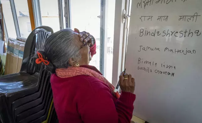 Sushila Gautam, 77 laughs as she becomes nervous before writing her name on the board during a writing practice in a class at the Ujyalo Community learning center in Kathmandu, Nepal, Feb. 3, 2025. (AP Photo/Niranjan Shrestha)