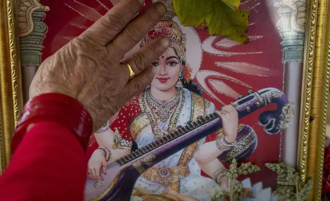 An elderly woman student worships a picture of Saraswati, Hindu goddess of wisdom and education before the start of a class at the Ujyalo Community learning center in Kathmandu, Nepal, Feb. 3, 2025. (AP Photo/Niranjan Shrestha)