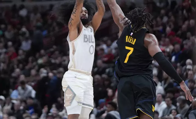 Golden State Warriors guard Buddy Hield (7) tries to block Chicago Bulls guard Coby White (0) who shoots a 3-point basket during the first half of an NBA basketball game Saturday, Feb. 8, 2025, in Chicago. (AP Photo/Erin Hooley)