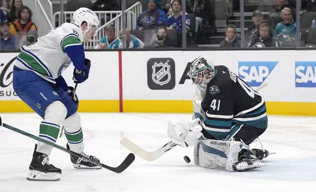 San Jose Sharks goaltender Vitek Vanecek (41) blocks a shot on goal by Vancouver Canucks left wing Drew O'Connor, left, during the second period of an NHL hockey game in San Jose, Calif., Thursday, Feb. 6, 2025. (AP Photo/Tony Avelar)