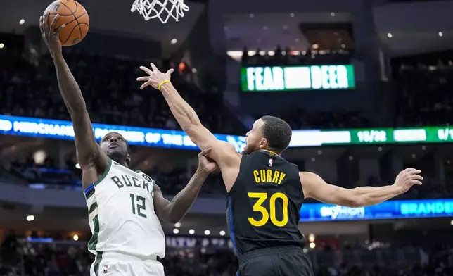 Milwaukee Bucks' Taurean Prince (12) looks to shoot against Golden State Warriors' Stephen Curry (30) during the first half of an NBA basketball game Monday, Feb. 10, 2025, in Milwaukee. (AP Photo/Andy Manis)