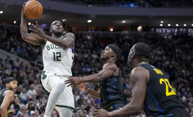 Milwaukee Bucks' Taurean Prince (12) shoots looks to shoot against Golden State Warriors' Jimmy Butler, second from right, and Draymond Green (23) during the first half of an NBA basketball game Monday, Feb. 10, 2025, in Milwaukee. (AP Photo/Andy Manis)