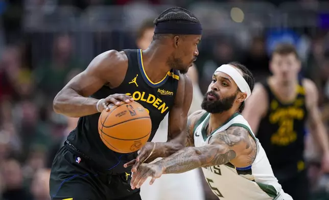 Milwaukee Bucks' Gary Trent Jr. (5) reaches in against Golden State Warriors' Jimmy Butler, left, during the first half of an NBA basketball game Monday, Feb. 10, 2025, in Milwaukee. (AP Photo/Andy Manis)