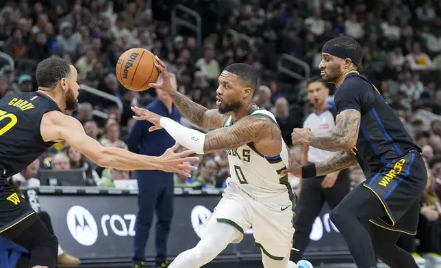 Milwaukee Bucks' Damian Lillard (0) looks to pass thee ball against Golden State Warriors' Stephen Curry, left, during the first half of an NBA basketball game Monday, Feb. 10, 2025, in Milwaukee. (AP Photo/Andy Manis)