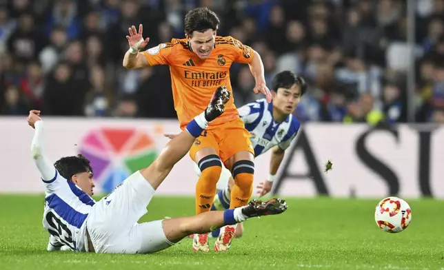 Real Madrid's Fran Garcia, centre, challenges for the ball with Real Sociedad's Jon Aramburu, left, during the Spanish Copa del Rey soccer match between Real Sociedad and Real Madrid at the Reale Arena in San Sebastian, Spain, Wednesday, Feb. 26, 2025. (AP Photo/Miguel Oses)