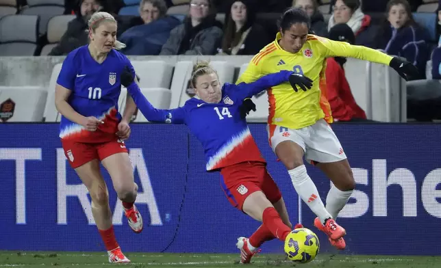 United States defender Emily Sonnett (14) slide tackles against Colombia forward Mayra Ramirez, right, as midfielder Lindsey Heaps (10) looks on during the SheBelieves Cup women's soccer tournament, Thursday, Feb. 20, 2025, in Houston. (AP Photo/Michael Wyke)