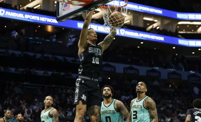 San Antonio Spurs forward Jeremy Sochan (10) dunks as Charlotte Hornets forward Miles Bridges (0) and guard DaQuan Jeffries (3) watch during the first half of an NBA basketball game in Charlotte, N.C., Friday, Feb. 7, 2025. (AP Photo/Nell Redmond)