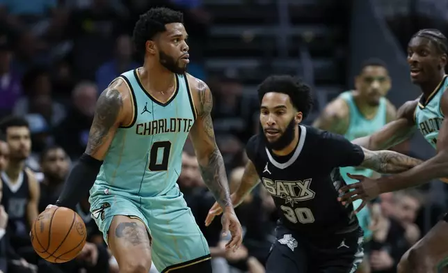 Charlotte Hornets forward Miles Bridges (0) looks to pass the ball against San Antonio Spurs forward Julian Champagnie (30) during the first half of an NBA basketball game in Charlotte, N.C., Friday, Feb. 7, 2025. (AP Photo/Nell Redmond)