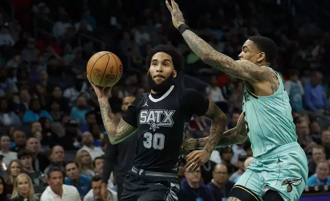 San Antonio Spurs forward Julian Champagnie (30) drives to the basket against Charlotte Hornets guard DaQuan Jeffries, right, during the first half of an NBA basketball game in Charlotte, N.C., Friday, Feb. 7, 2025. (AP Photo/Nell Redmond)