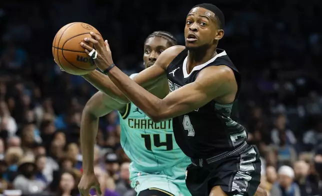 San Antonio Spurs guard De'Aaron Fox (4) looks to pass the ball ahead of Charlotte Hornets forward Moussa Diabate, left, during the first half of an NBA basketball game in Charlotte, N.C., Friday, Feb. 7, 2025. (AP Photo/Nell Redmond)