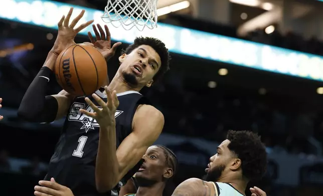 San Antonio Spurs center Victor Wembanyama (1) pulls down an offensive rebound against Charlotte Hornets forwards Moussa Diabate, center, and Miles Bridges, right, during the first half of an NBA basketball game in Charlotte, N.C., Friday, Feb. 7, 2025. (AP Photo/Nell Redmond)