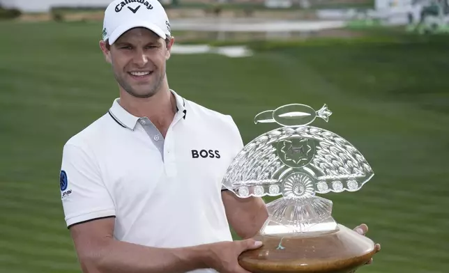 Thomas Detry, of Belgium, smiles as celebrates after his win at the Phoenix Open golf tournament at TPC Scottsdale while holding the winner's trophy and posing for photographers Sunday, Feb. 9, 2025, in Scottsdale, Ariz. (AP Photo/Ross D. Franklin)