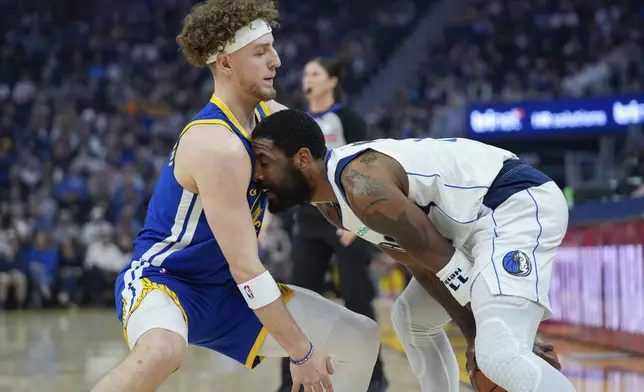 Dallas Mavericks guard Kyrie Irving, right, tries to move the ball while defended by Golden State Warriors guard Brandin Podziemski during the first half of an NBA basketball game Sunday, Feb. 23, 2025, in San Francisco. (AP Photo/Godofredo A. Vásquez)