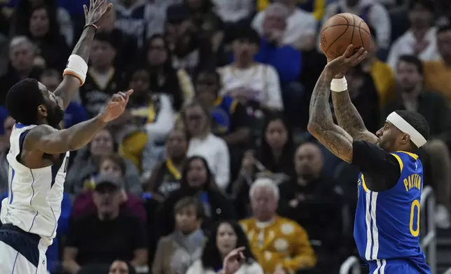 Golden State Warriors guard Gary Payton II, right, shoots a 3-point basket over Dallas Mavericks guard Kyrie Irving during the first half of an NBA basketball game Sunday, Feb. 23, 2025, in San Francisco. (AP Photo/Godofredo A. Vásquez)