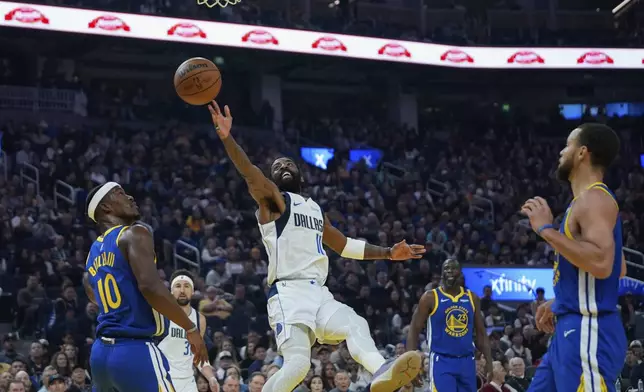 Dallas Mavericks guard Kyrie Irving, center, shoots next to Golden State Warriors forward Jimmy Butler III, left, during the first half of an NBA basketball game Sunday, Feb. 23, 2025, in San Francisco. (AP Photo/Godofredo A. Vásquez)