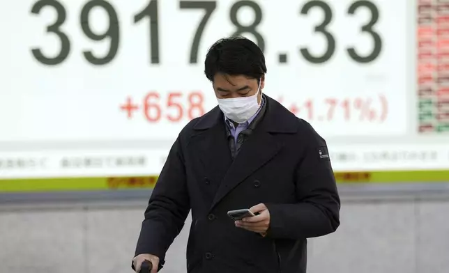 A person walks in front of an electronic stock board showing Japan's Nikkei index at a securities firm Tuesday, Feb. 4, 2025, in Tokyo. (AP Photo/Eugene Hoshiko)