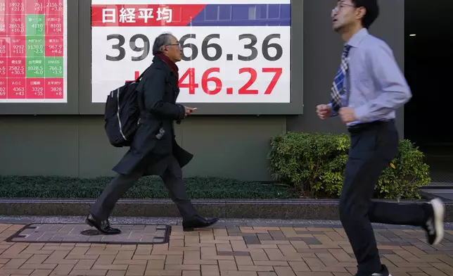 People walk in front of an electronic stock board showing Japan's Nikkei index at a securities firm Tuesday, Feb. 4, 2025, in Tokyo. (AP Photo/Eugene Hoshiko)