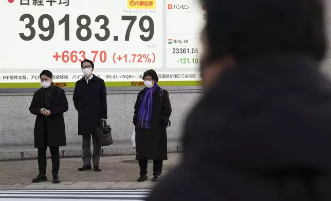 People stand in front of an electronic stock board showing Japan's Nikkei index at a securities firm Tuesday, Feb. 4, 2025, in Tokyo. (AP Photo/Eugene Hoshiko)