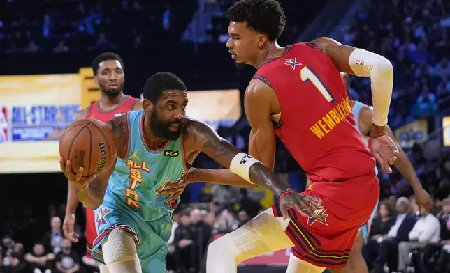 Dallas Mavericks guard Kyrie Irving, left, dribbles past San Antonio Spurs center Victor Wembanyama during the NBA All-Star basketball game Sunday, Feb. 16, 2025, in San Francisco. (AP Photo/Godofredo A. Vásquez)