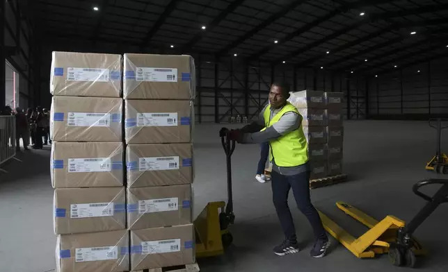 A National Electoral Council employee moves boxes of election materials to be taken to a polling station in preparation for Sunday's general election, in Quito, Ecuador, Saturday, Feb. 8, 2025. (AP Photo/Dolores Ochoa)