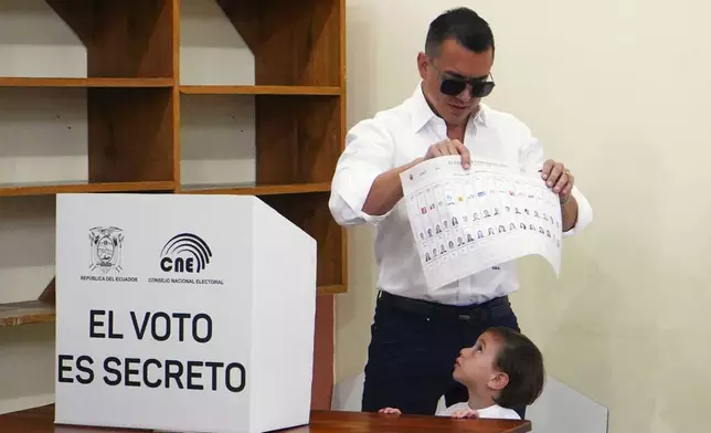 President Daniel Noboa, who is running for reelection, holds up his ballot before voting in the presidential election in Olon, Ecuador, Sunday, Feb. 9, 2025. (AP Photo/Cesar Munoz)