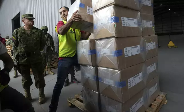 A National Electoral Council employee helps to load electoral kits at a distribution center, in preparation for Sunday's general election, in Quito, Ecuador, Saturday, Feb. 8, 2025. (AP Photo/Dolores Ochoa)