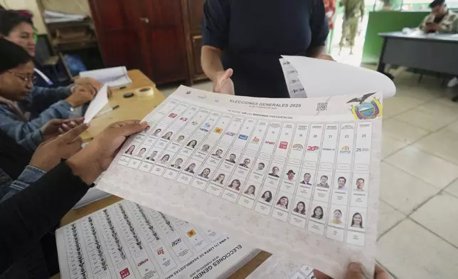 An electoral official hands a ballot to a voter during the presidential election in Quito, Ecuador, Sunday, Feb. 9, 2025. (AP Photo/Dolores Ochoa)