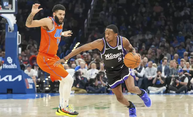 Sacramento Kings guard De'Aaron Fox, right, drives past Oklahoma City Thunder forward Kenrich Williams, left, during the first half of an NBA basketball game, Saturday, Feb. 1, 2025, in Oklahoma City. (AP Photo/Kyle Phillips)