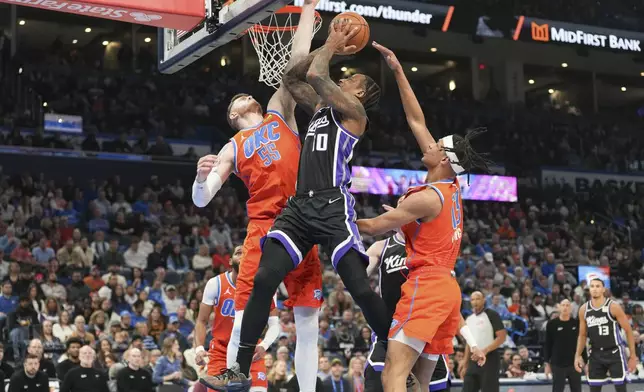 Sacramento Kings forward DeMar DeRozan, middle, shoots over Oklahoma City Thunder center Isaiah Hartenstein, left, and forward Ousmane Dieng, right, during the first half of an NBA basketball game, Saturday, Feb. 1, 2025, in Oklahoma City. (AP Photo/Kyle Phillips)