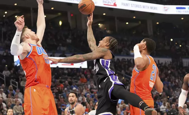 Sacramento Kings forward DeMar DeRozan, center, shoots over Oklahoma City Thunder center Isaiah Hartenstein, left, and guard Aaron Wiggins, right, during the first half of an NBA basketball game, Saturday, Feb. 1, 2025, in Oklahoma City. (AP Photo/Kyle Phillips)