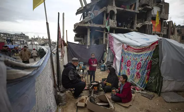 A Palestinian family cooks on fire next to their tent, in an area largely destroyed by the Israeli army's air and ground offensive in Jabaliya, Gaza Strip, on Tuesday, Feb. 11, 2025. (AP Photo/Jehad Alshrafi)