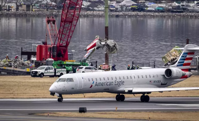 A crane offloads a piece of wreckage from a salvage vessel onto a flatbed truck, near the wreckage site in the Potomac River of a mid-air collision between an American Airlines jet and a Black Hawk helicopter, at Ronald Reagan Washington National Airport, Wednesday, Feb. 5, 2025, in Arlington, Va. (AP Photo/Ben Curtis)