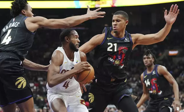 Cleveland Cavaliers' Evan Mobley, center, protects the ball from Toronto Raptors' Scottie Barnes, left, and Orlando Robinson (21) during the first half of an NBA basketball game in Toronto, Wednesday, Feb. 12, 2025. (Frank Gunn/The Canadian Press via AP)