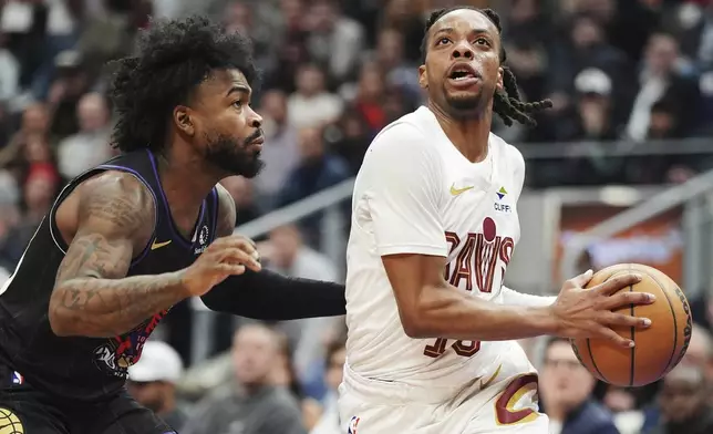 Cleveland Cavaliers' Darius Garland, right, drives past Toronto Raptors' Jamal Shead (23) during the first half of an NBA basketball game in Toronto, Wednesday, Feb. 12, 2025. (Frank Gunn/The Canadian Press via AP)
